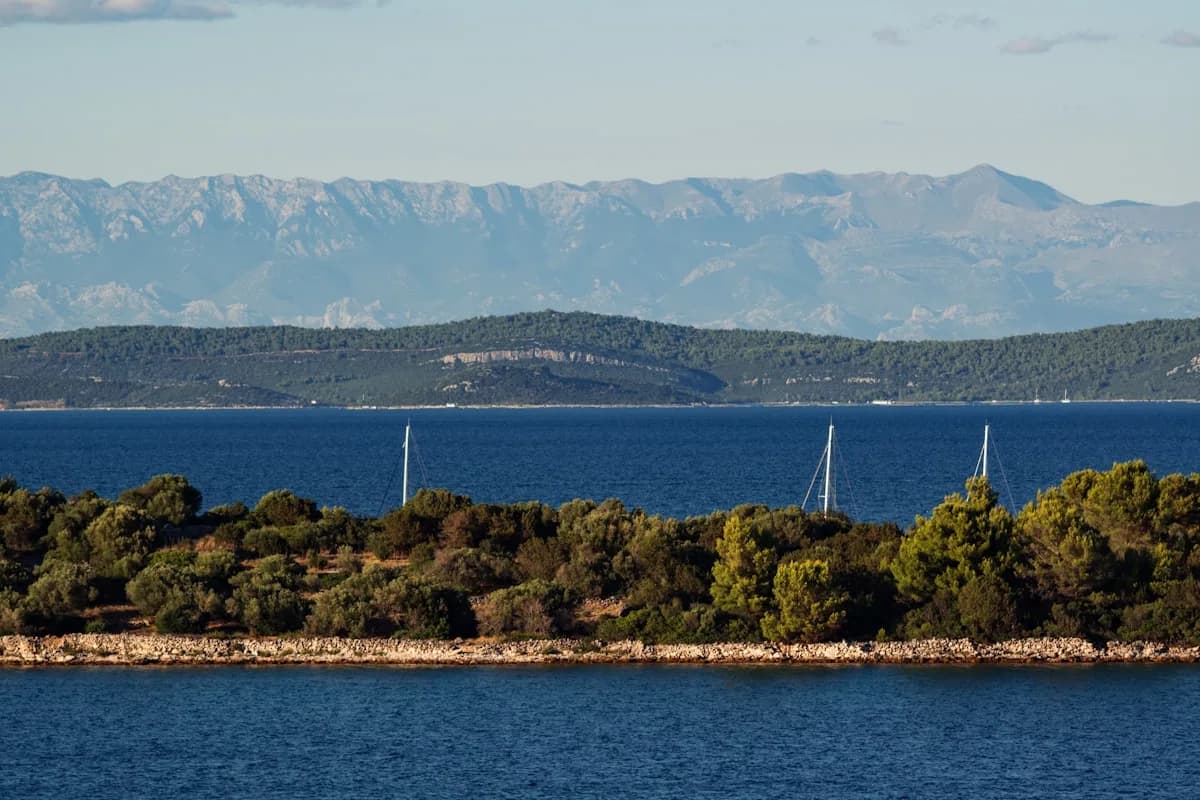 Zeilboten op een kalme Adriatische Zee met Kroatische eilanden en bergen op de achtergrond